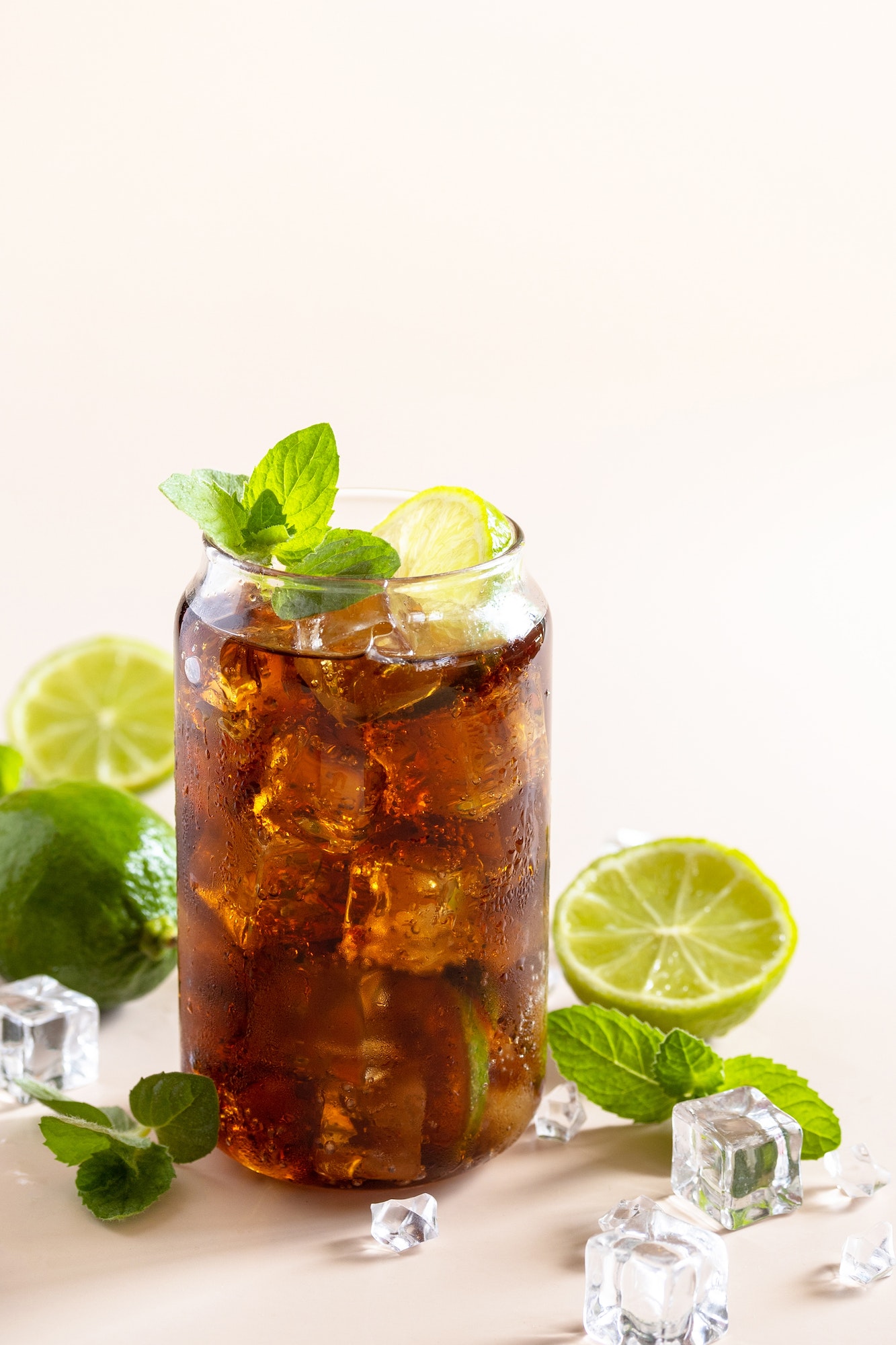 Cola with ice cubes or lemonade on a pastel brown background. Copy space.